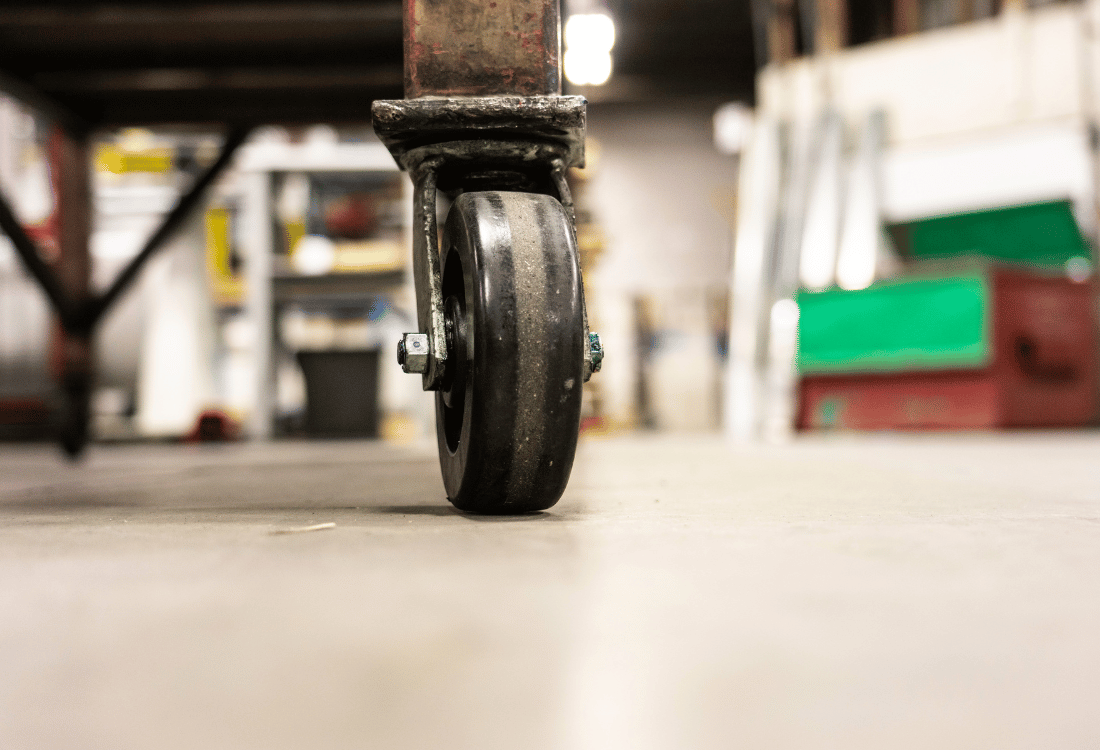 A castor wheel on a shop floor is currently struggling due to not being kept in top shape with maintenance.