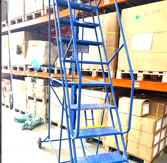 Blue mobile safety steps positioned beside warehouse racking to provide safe elevated access for stock picking and storage tasks.