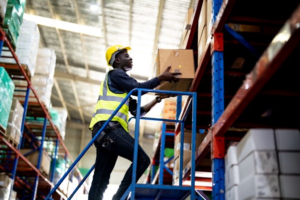 Warehouse worker using warehouse steps to safely access stock stored on high-level racking.