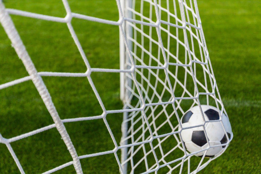 A player making a goal into a football net.