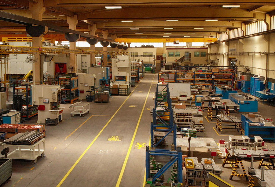 A spacious, well-organised industrial workshop filled with machinery, workstations, and storage racks.