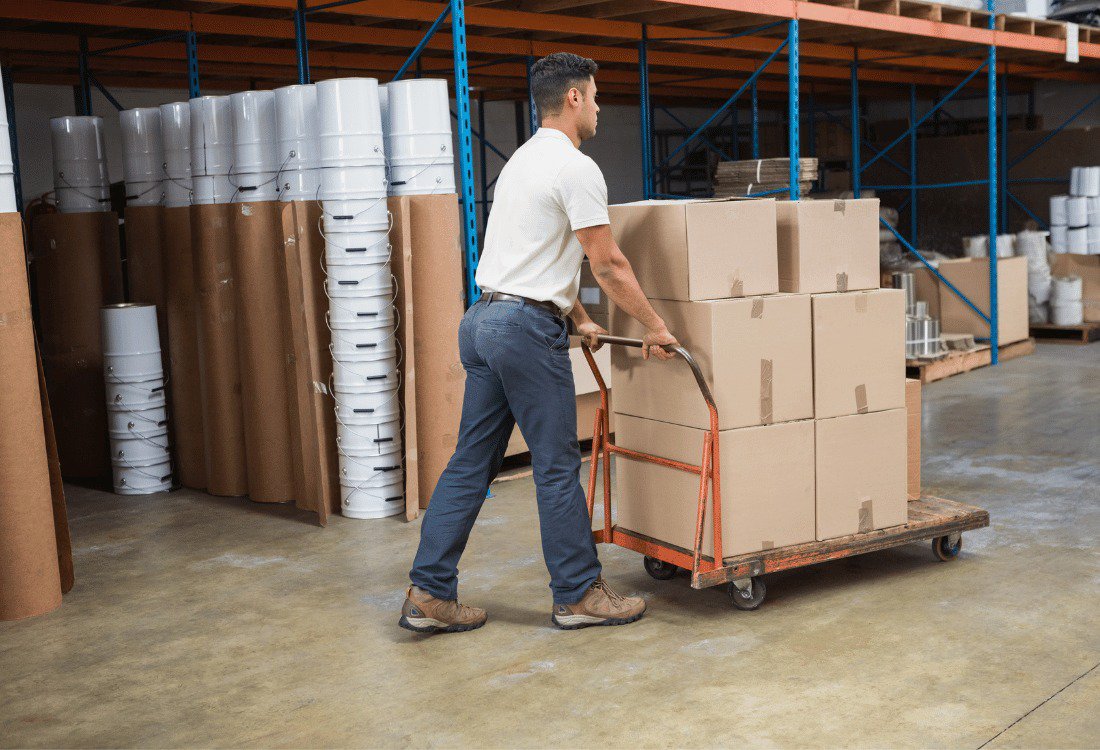 A male warehouse worker pushing a trolley using quieter castors to reduce industrial noise pollution.