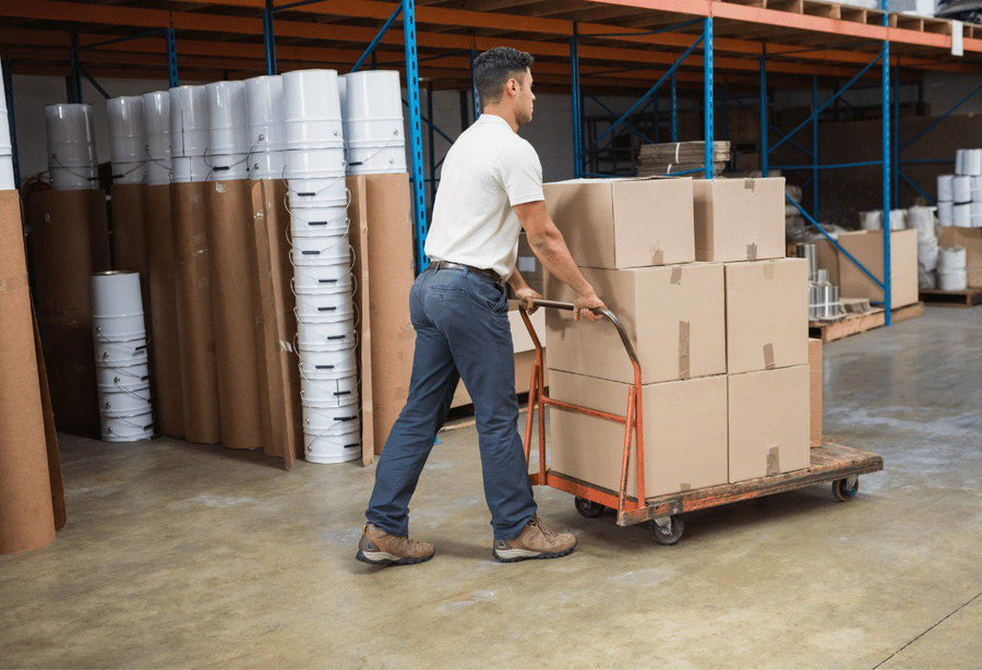 A male warehouse worker pushing a trolley using quieter castors to reduce industrial noise pollution.
