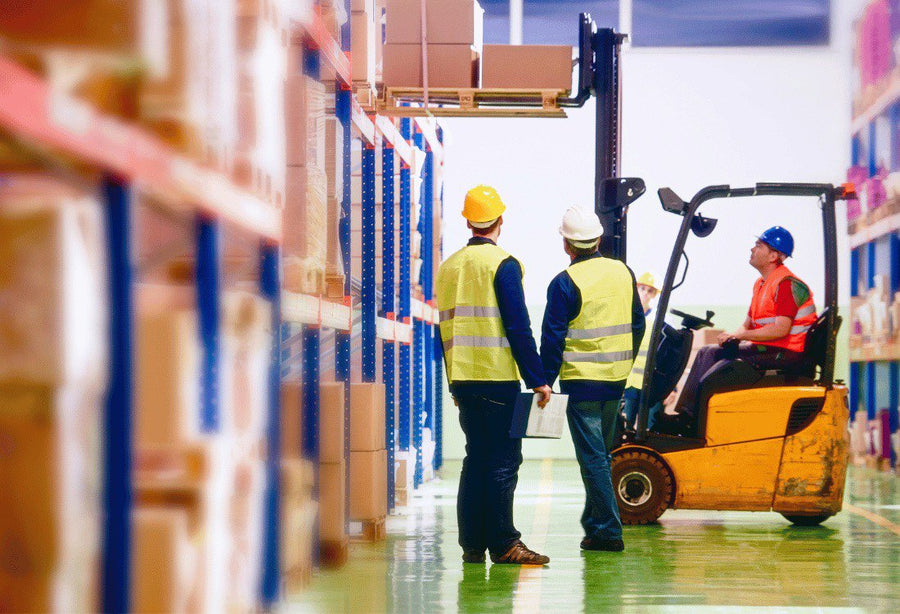 Warehouse workers working safely with impact protection barriers in the background.