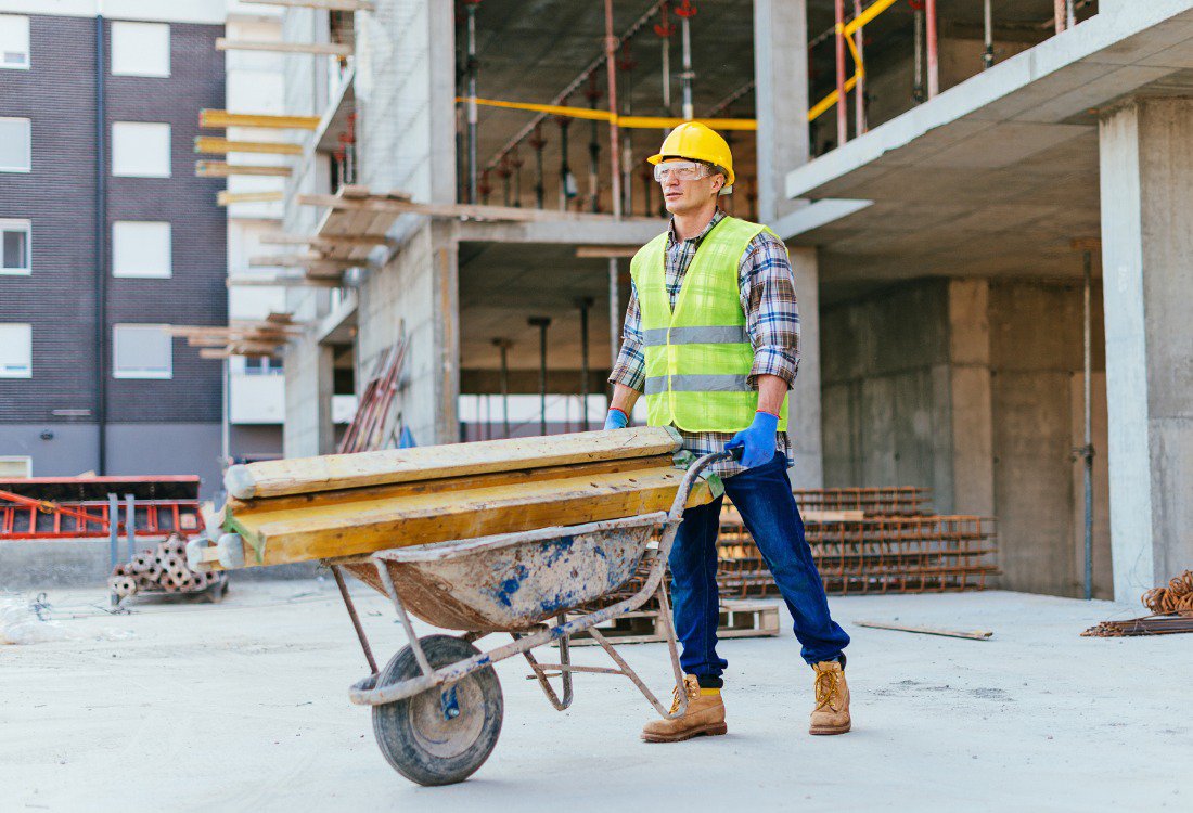 A builder using a wheelbarrow on a building site.